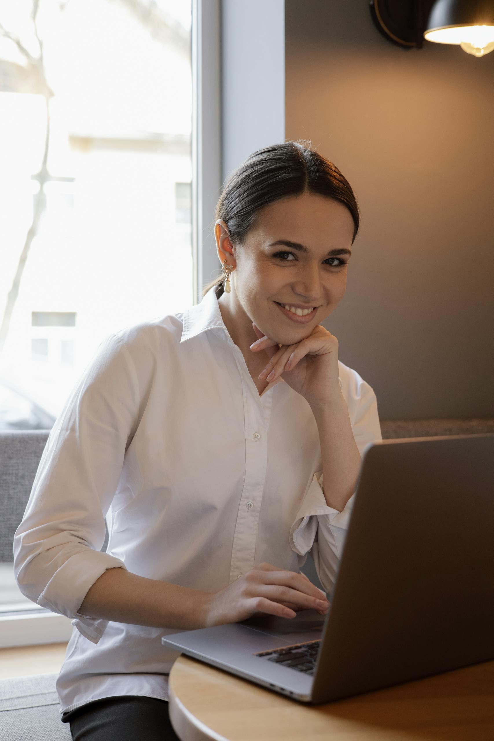 Professional woman in casual setting, using laptop at a cafe.